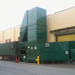 20-foot-wide roll-up door walled in on the bottom section, top left open for ventilation. Enters into a staging area where extended height dumper (18 foot) is rear loaded into a CP155FW feeding a walking trailer (special application).